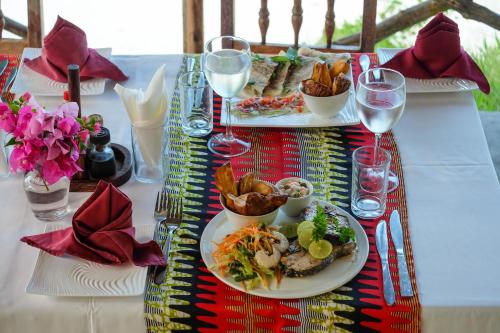 a table with two plates of food and wine glasses at Seasons Lodge Zanzibar in Pongwe