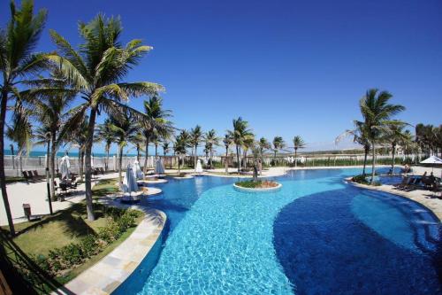 a pool at a resort with palm trees at Apartamento - Resort Golf Ville in Aquiraz