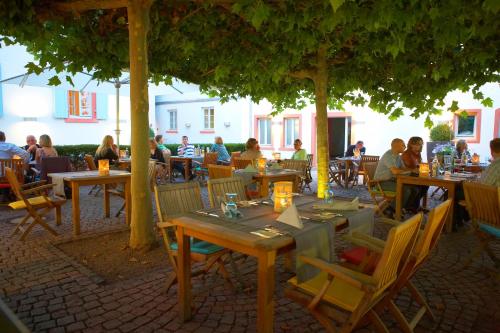 eine Gruppe von Menschen, die an Tischen unter einem Baum sitzen in der Unterkunft Landhotel zum Schwanen mit Restaurant Mona Liza in Osthofen