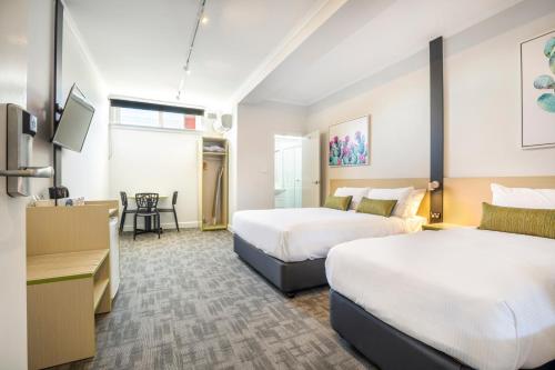 ein Hotelzimmer mit 2 Betten und einem Schreibtisch in der Unterkunft Nightcap at Hume Hotel in Bankstown