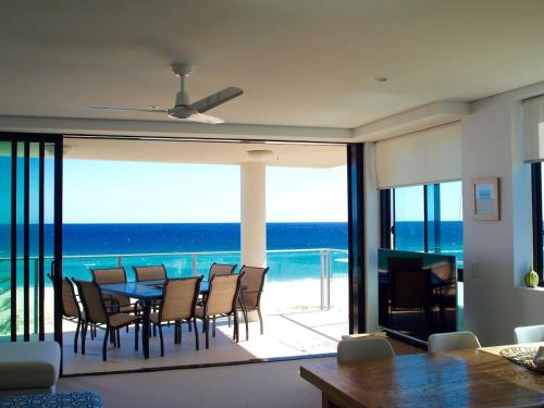 una sala da pranzo con tavolo, sedie e vista sull'oceano di Pure Kirra a Gold Coast