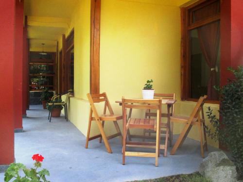 un patio con mesa, sillas y una pared amarilla en El Portal del Lago en Lago Puelo