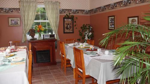 uma sala de jantar com mesas brancas e uma lareira em Arkadia Eastman B&B em Eastman