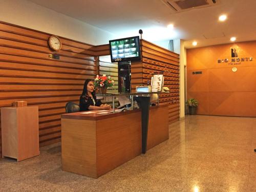 a woman sitting at a reception desk in a lobby at Rio Monte Residence in Bangkok