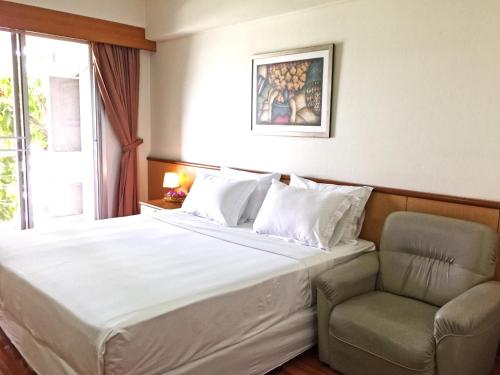a hotel room with a bed and a chair at Rio Monte Residence in Bangkok