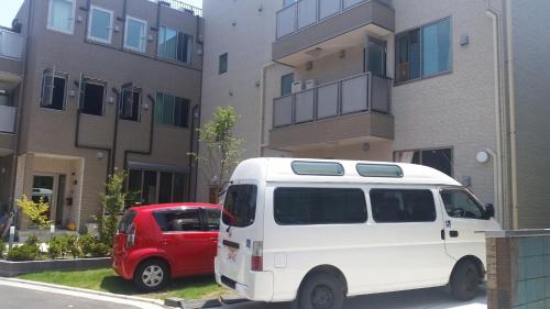 a white van and a red car parked in front of a building at Tokyo Guest House 2020 in Tokyo