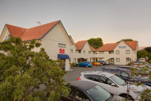 a hotel with cars parked in a parking lot at Bella Vista Motel Rotorua in Rotorua