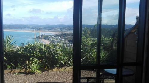 a view of a beach from a window at Ocean Purring Views in Tutukaka