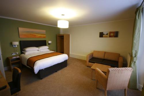 a hotel room with a bed and a chair at Thomas Arms Hotel in Llanelli