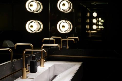 a bathroom with a sink and mirrors and lights at Tribe Perth Kings Park in Perth