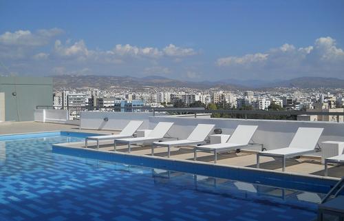 a group of white lounge chairs next to a swimming pool at Eden Dream Apartments in Limassol