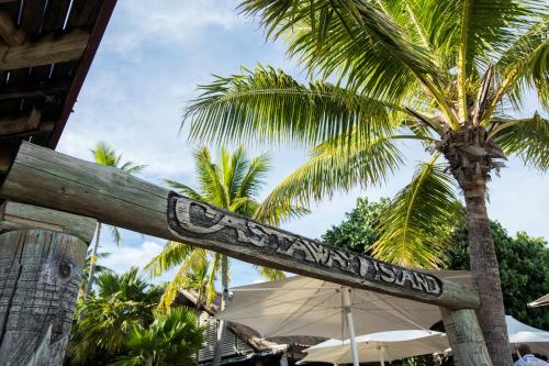 a sign for a restaurant with palm trees in the background at Castaway Island, Fiji in Castaway Island