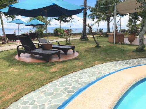 two chairs and an umbrella next to a swimming pool at Cabilao Sunset Dive & Beach Resort in Loon