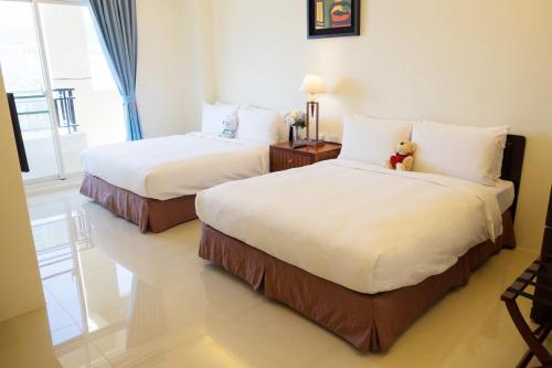 two beds in a hotel room with a teddy bear on them at Na Na Ya Ji Bed and Breakfast in Taitung City