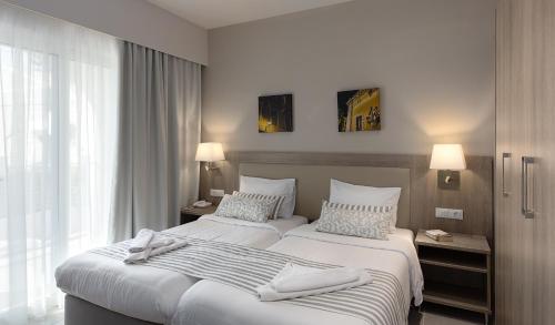 a hotel room with two beds with towels on them at Acharavi Beach Hotel in Acharavi