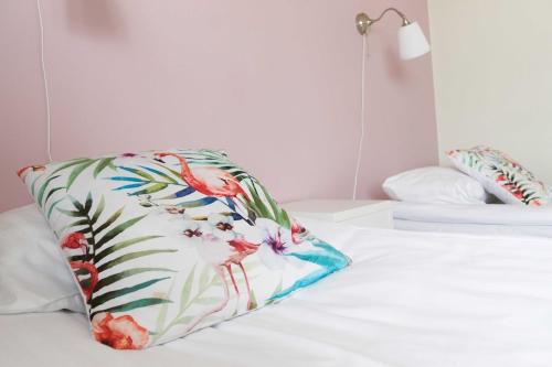 a white bed with a colorful pillow on it at Pensionat Augustin in Gällivare