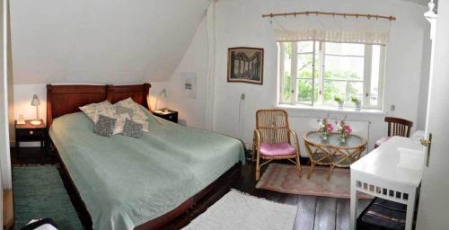 1 dormitorio con cama, escritorio y ventana en Danchelshus, en Allinge