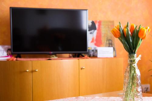 a vase with orange tulips in front of a tv at Airport Apartments in Belgrade
