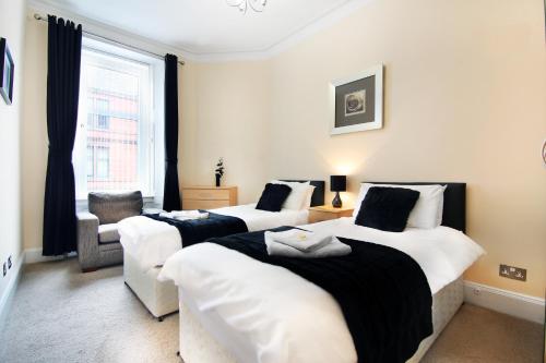 a bedroom with two beds and a chair and a window at Townhead Apartments Glasgow Airport in Paisley