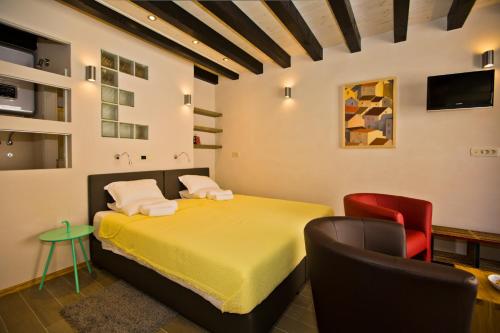 a bedroom with a yellow bed and two chairs at St. Stephen's Square Apartment in Hvar