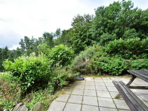 un giardino con panchina e alcuni cespugli e alberi di Cosy chalet in Li zey with countryside views a Liézey