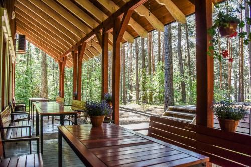 a porch with benches and tables in the woods at Camping Mindunai in Mindūnai