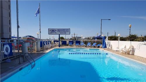 a large swimming pool with blue water and chairs at The Schooner Inn in Virginia Beach