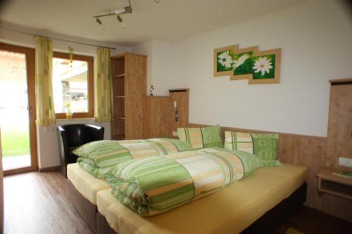 a bedroom with a bed with green and white sheets at Landhaus Alpensonne in Neustift im Stubaital