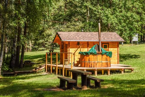a small wooden cabin with a playground in the grass at Camping Mindunai in Mindūnai