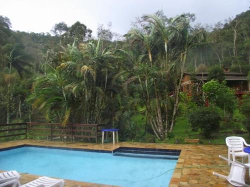 a swimming pool in front of a resort with palm trees at Pousada Romântica Serra da Mata in Penedo