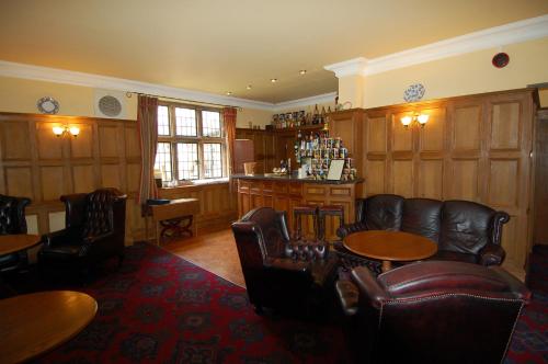 um quarto com cadeiras e mesas de couro e um bar em Dunsley Hall Country House Hotel em Whitby