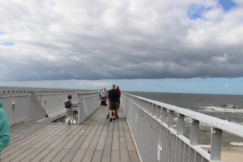 a group of people walking on a pier at Apartament Nordic in Trzęsacz