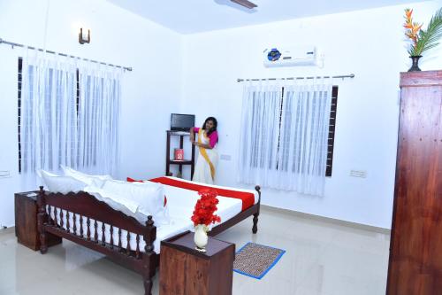 a woman standing in a room with a bed at Marari Bethsaida Homestay in Shertallai