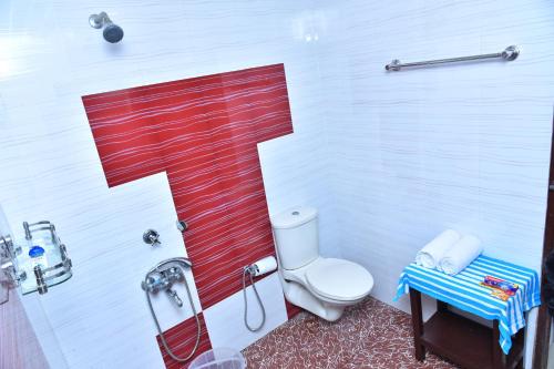 a bathroom with a toilet with a red stripe on the wall at Marari Bethsaida Homestay in Shertallai
