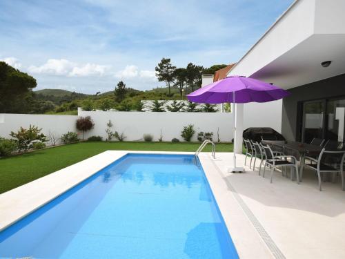 a swimming pool with a purple umbrella next to a house at Modern villa with private swimming pool near Nazar in Famalicão