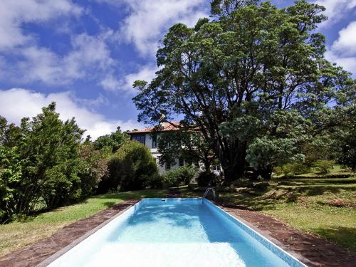 a blue swimming pool in the yard of a house at Beautiful house on the garden island of Madeira in Santo da Serra