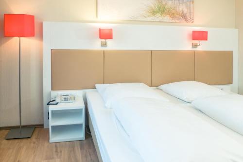 a bedroom with two beds and a nightstand with two lamps at Hotel Stuttgart Sindelfingen City by Tulip Inn in Sindelfingen