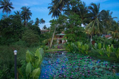 a pond in front of a resort with colorful flowers at Hotel Birds View in Tissamaharama