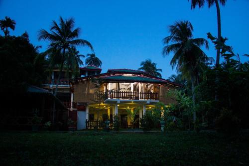 a house with a balcony and palm trees at night at Hotel Birds View in Tissamaharama