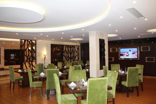 a restaurant with green chairs and tables and a tv at AlMuhaidb Residence Alkhafji in Al Khafji