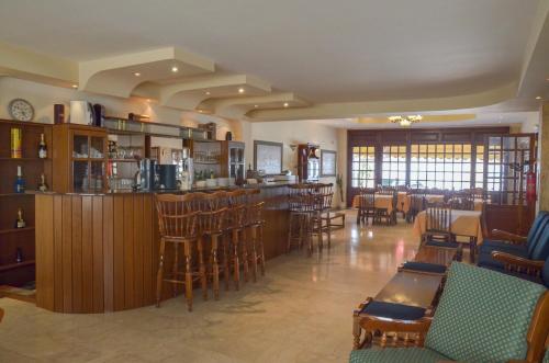 un restaurante con bar y algunas sillas y mesas en Hotel Costis en Ptolemaida