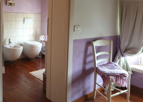 a bathroom with a toilet and a chair in it at Agriturismo Casa Aurora in Bussolengo