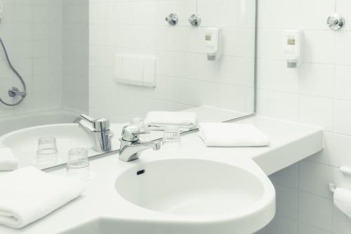 a white bathroom with a toilet and a sink at Hotel Stuttgart Sindelfingen City by Tulip Inn in Sindelfingen