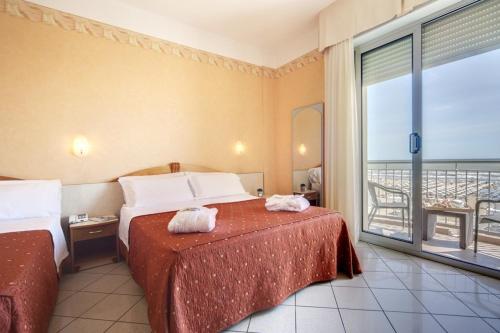 um quarto de hotel com uma cama e uma varanda em Hotel Ambra em Rimini