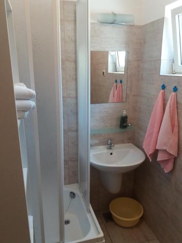 La salle de bains est pourvue d'un lavabo, d'une douche et de serviettes roses. dans l'établissement Amber House Apartments Supetar-Brac, à Supetar