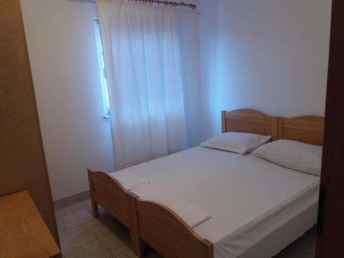 - une chambre avec un lit doté de draps blancs et une fenêtre dans l'établissement Amber House Apartments Supetar-Brac, à Supetar