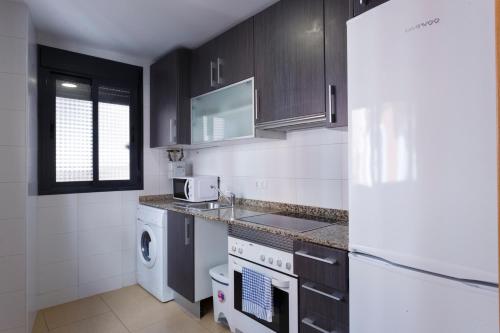 eine Küche mit schwarzen Schränken und einem weißen Gerät in der Unterkunft Apartamentos Santa Barbara in Alicante