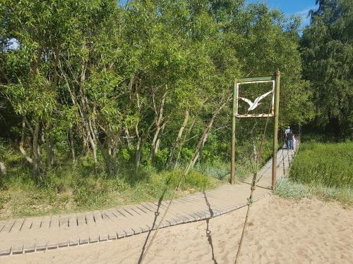 a sign on a fence in front of a forest at Pinedune Beach in Saulkrasti
