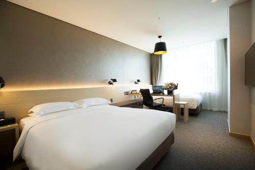 a hotel room with a large white bed and a desk at Arirang Hill Hotel Dongdaemun in Seoul