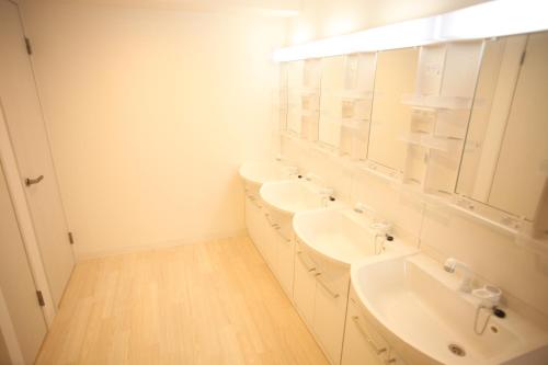 a white bathroom with two sinks and a mirror at Base Inn Tabata in Tokyo